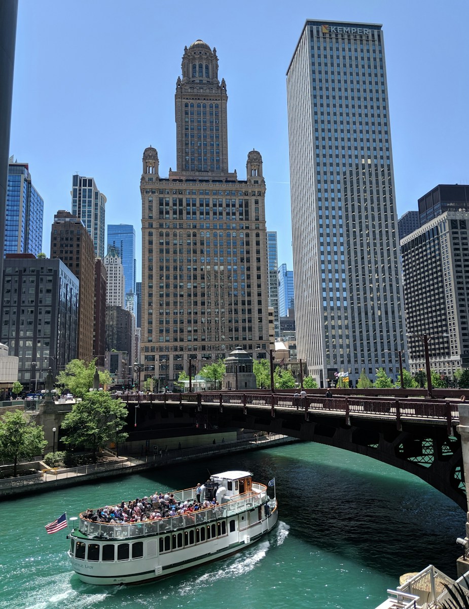 white boat with passengers crossing under bridge during daytime